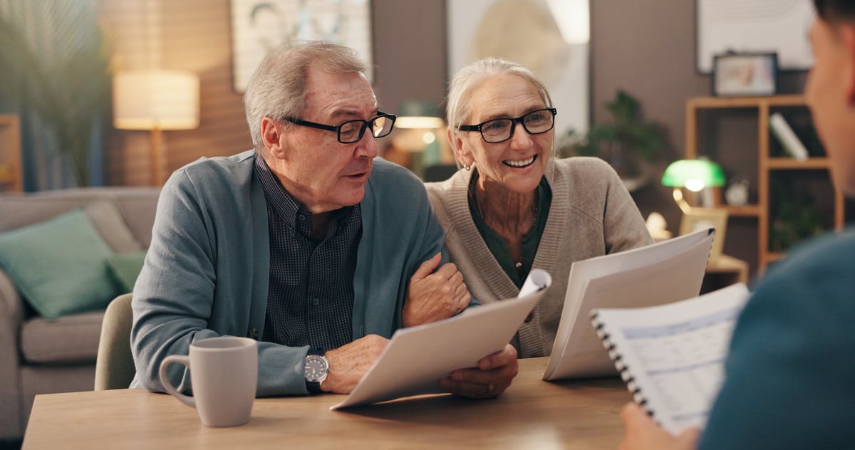 Elderly couple reviewing documents with financial advisor for estate planning