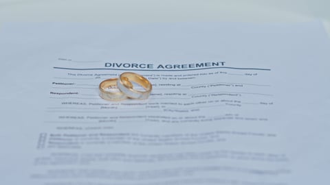 Divorce Agreement Document with Wedding Rings on Top